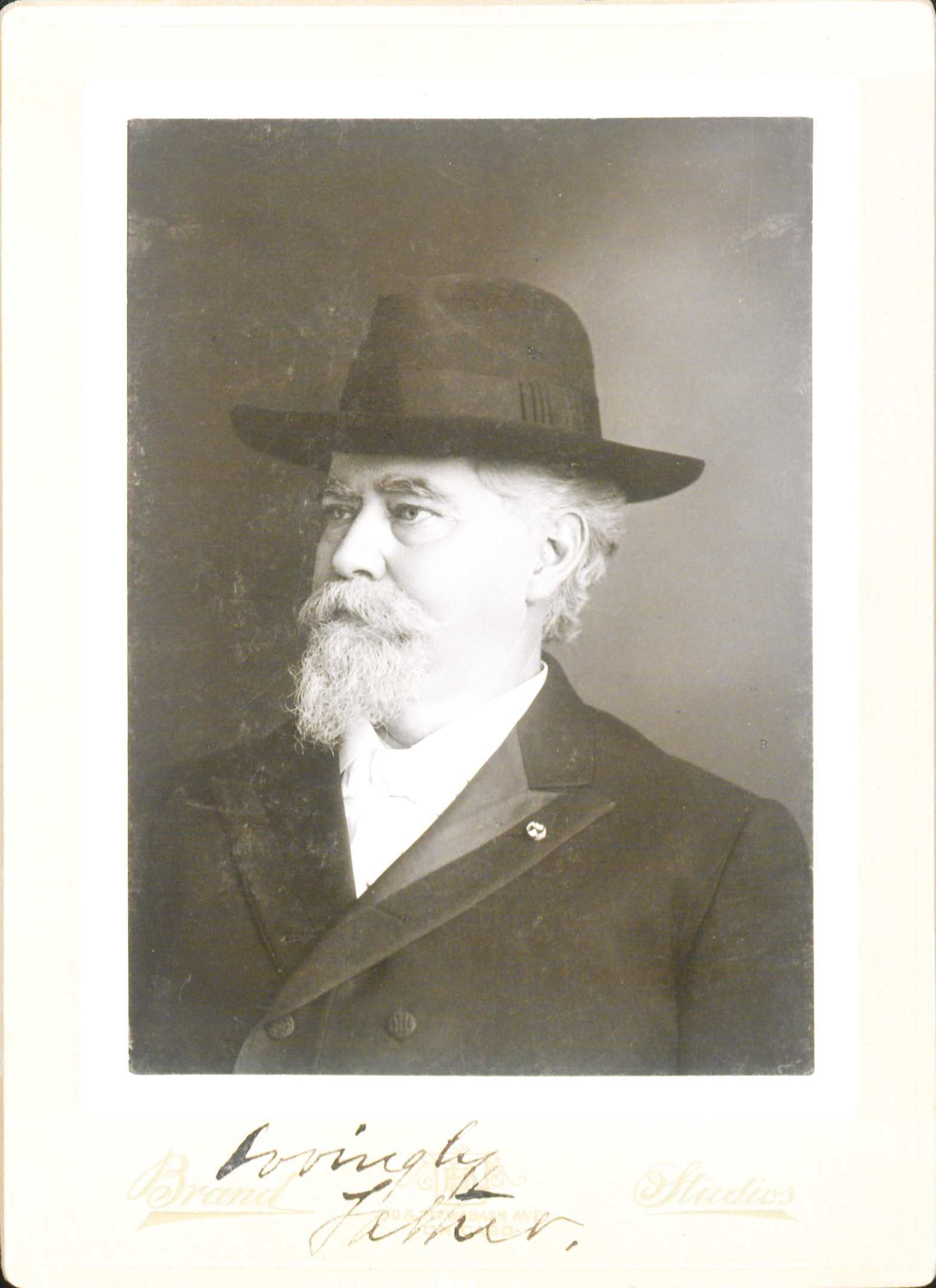 Portrait of John Black wearing a hat, and an overcoat. He is looking off to the left. He has white moustache and beard