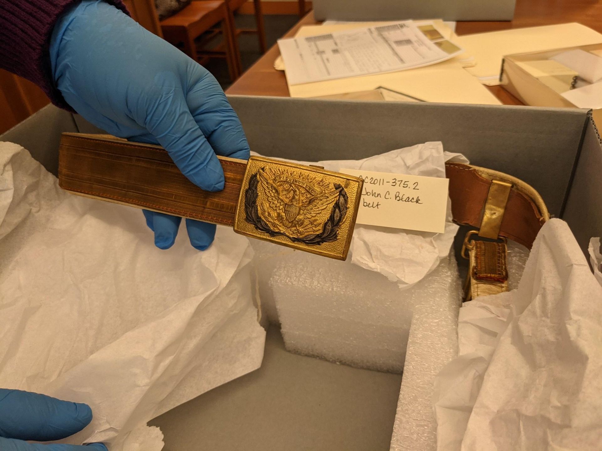 Picture of a hand wearing latex gloves holding a belt buckle
