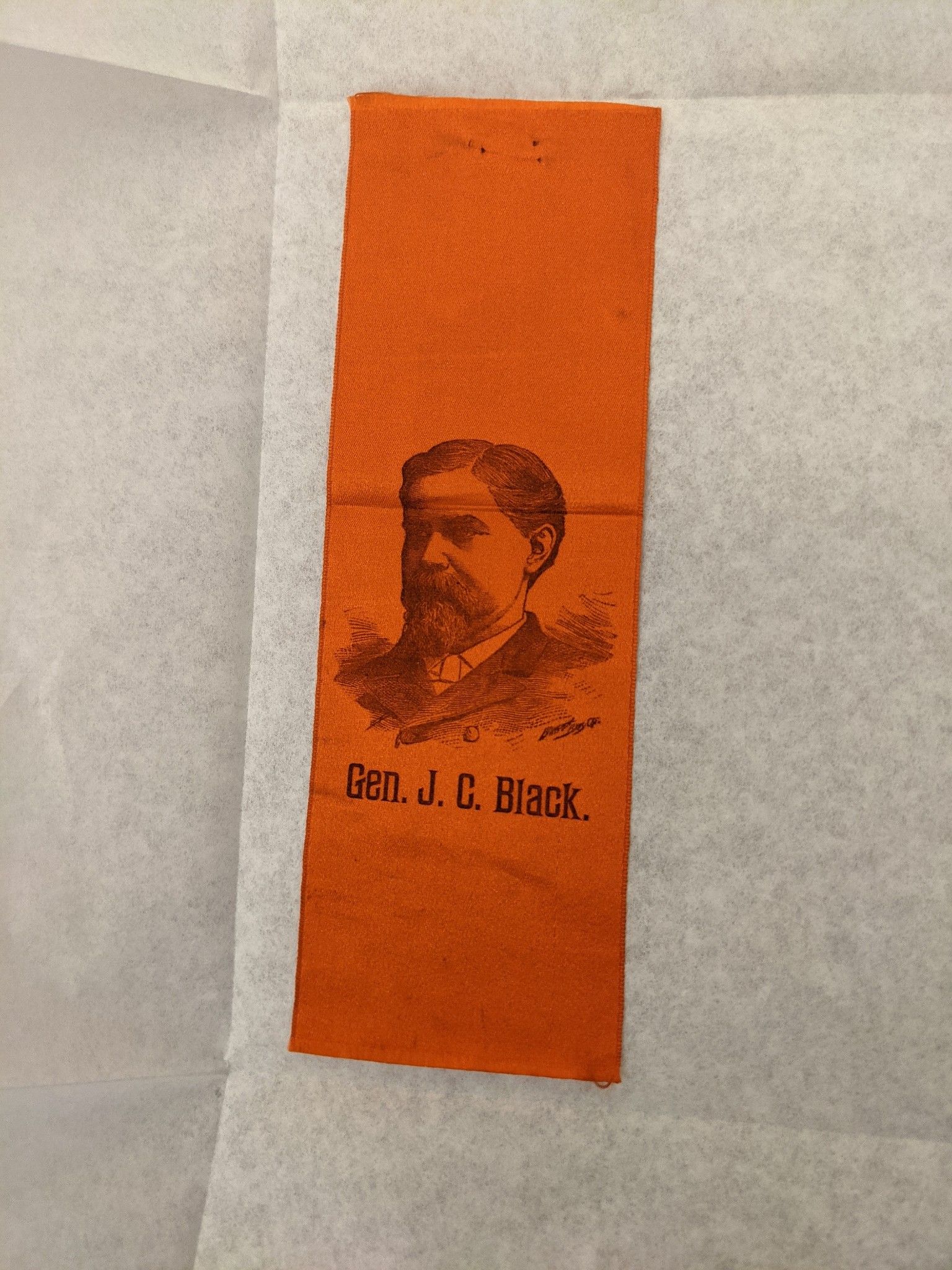 Picture of a Campaign Ribbon. The Ribbon is Orange with a picture of John Black's head and shoulders and the wrods Gen J.C. Black