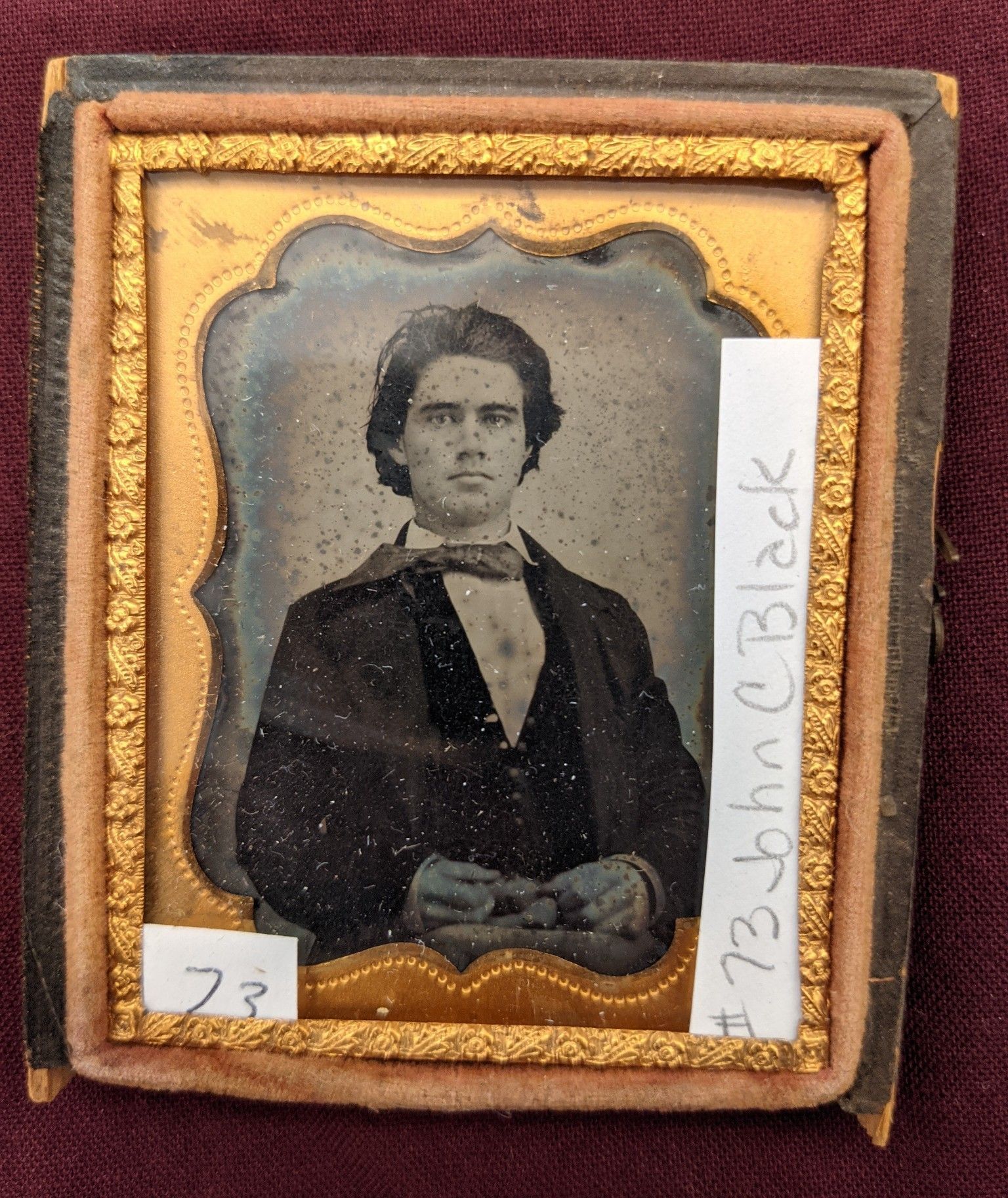 Portrait of a younger John Black inside a gold frame. He has a full set of hair and is wearing a 3 piece suitThere is a piece of paper with the name John C Black